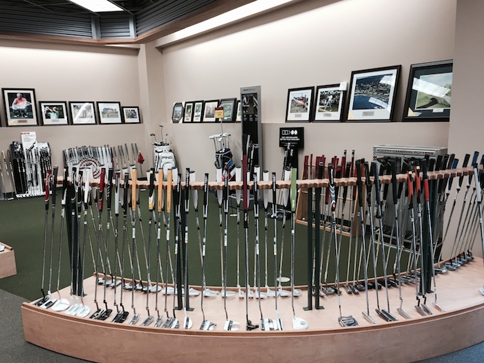 A long curved display of putters on the floor at Golf Headquarters